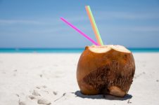 Um coco com canudos na areia da praia