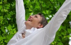 mulher com os braços abertos e sorrindo