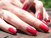 Mãos com as unhas dos dedos pintadas de esmalte vermelho