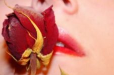 Mulher cheirando uma pétala de rosa