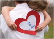 criança no colo do pai segurando um coração de papel