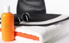 Chapéu, óculos de sol, protetor solar e toalha