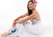 Mulher de vestido sentada com uma rosa na orelha