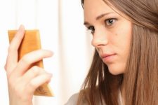 Mulher com acne no rosto olhando para o espelho