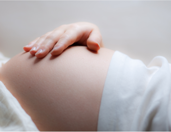 uma mão sobre a barriga de uma grávida