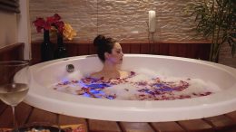 Mulher em uma banheira com espumas e pétalas de rosas